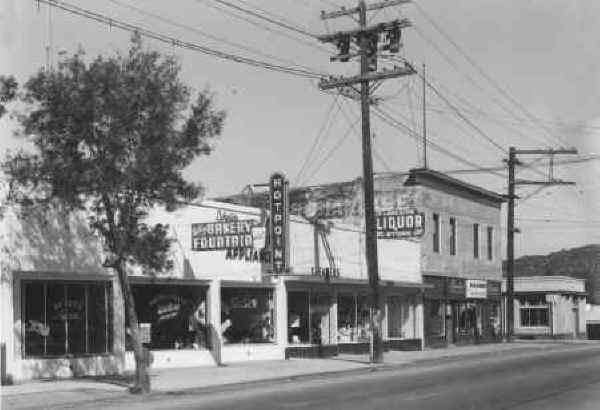 West side of Maine Ave, facing north: Beauty Salon, Watkins Bakery & Fountain Lakeside Appliances, Lakeside Liquor, M & H Market and bank on the corner. c. 03/19/1951